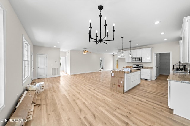 kitchen with white cabinetry, light hardwood / wood-style flooring, a kitchen island, and stainless steel appliances