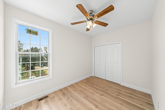 unfurnished bedroom with ceiling fan, light wood-type flooring, and a closet