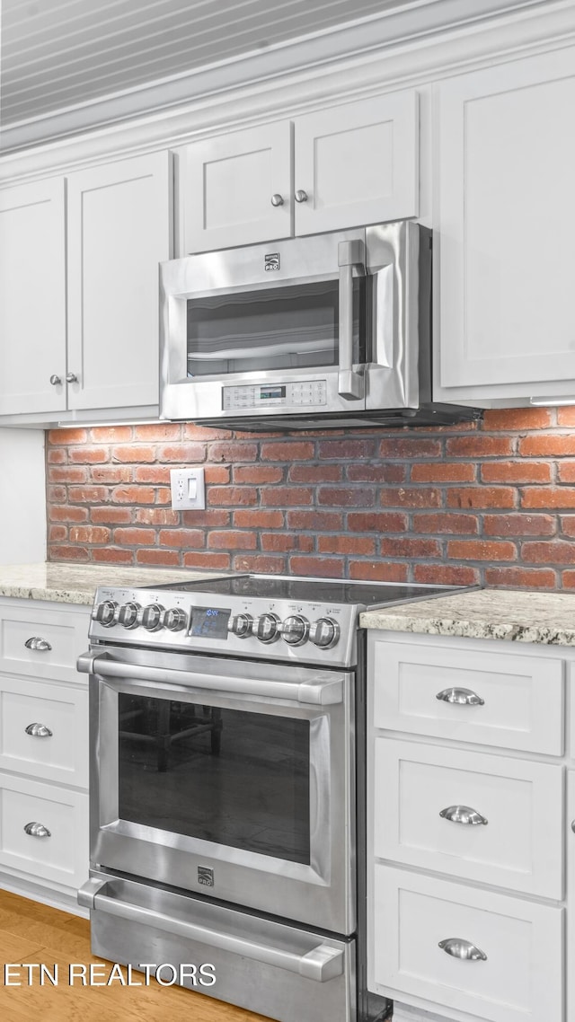 kitchen with light stone countertops, stainless steel appliances, and white cabinetry