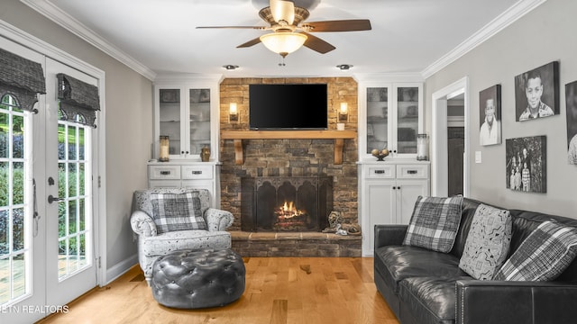 living room with crown molding, a fireplace, ceiling fan, and light wood-type flooring