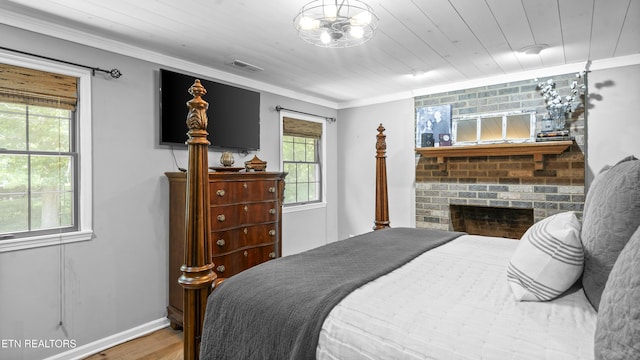 bedroom with wood ceiling, a fireplace, ornamental molding, and hardwood / wood-style flooring