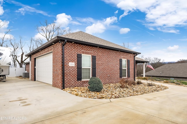 view of side of home featuring a garage and cooling unit