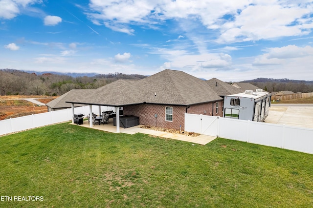 rear view of house with a yard, a hot tub, and a patio area