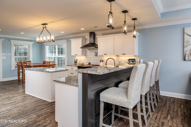 kitchen featuring dark hardwood / wood-style floors, white cabinets, pendant lighting, and wall chimney range hood