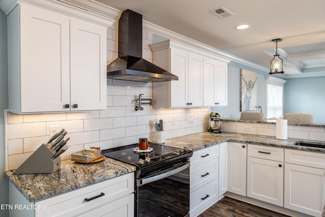 kitchen featuring wall chimney range hood, black electric range, backsplash, crown molding, and white cabinets