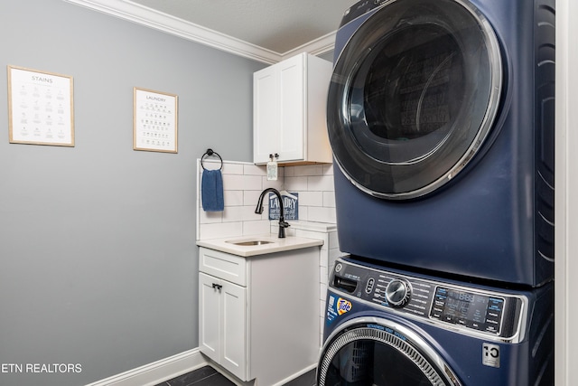 washroom featuring cabinets, crown molding, sink, and stacked washer / dryer