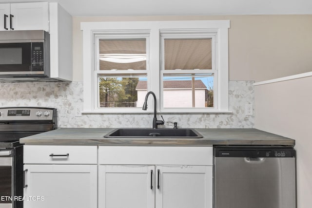 kitchen with white cabinets, appliances with stainless steel finishes, a healthy amount of sunlight, and sink