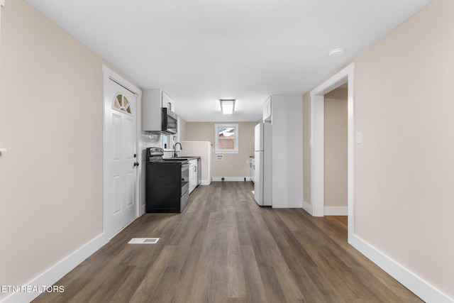 interior space featuring appliances with stainless steel finishes, dark hardwood / wood-style flooring, white cabinetry, and sink