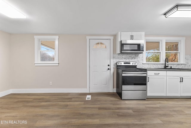 kitchen featuring backsplash, white cabinets, sink, light hardwood / wood-style floors, and stainless steel appliances