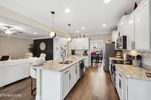 kitchen with white cabinets, a center island with sink, dark hardwood / wood-style floors, decorative backsplash, and stainless steel appliances