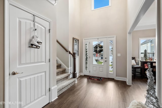 foyer entrance featuring crown molding, dark hardwood / wood-style flooring, and a towering ceiling