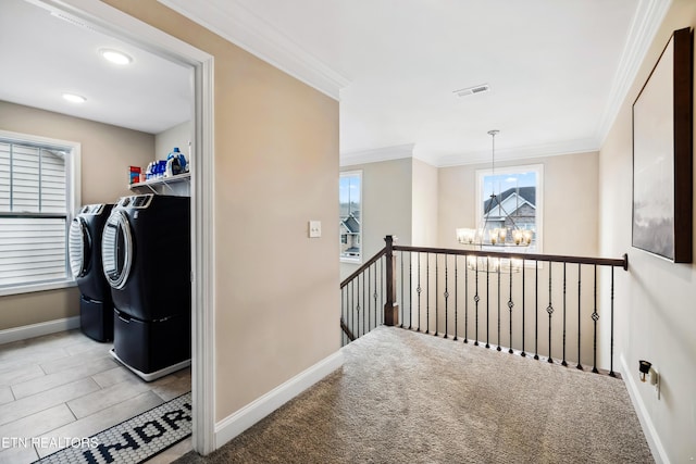 washroom featuring washing machine and dryer, light colored carpet, crown molding, and a chandelier