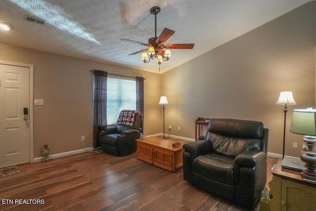 living area with ceiling fan, dark wood-type flooring, and a textured ceiling