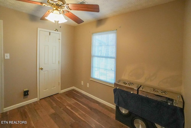 interior space with a textured ceiling, ceiling fan, and dark wood-type flooring