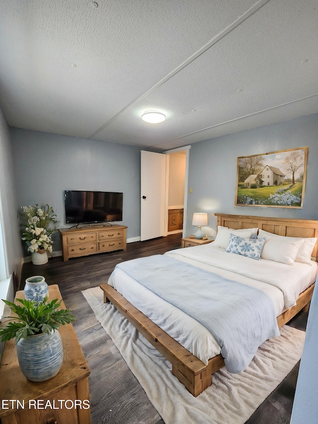 bedroom with dark hardwood / wood-style floors and a textured ceiling