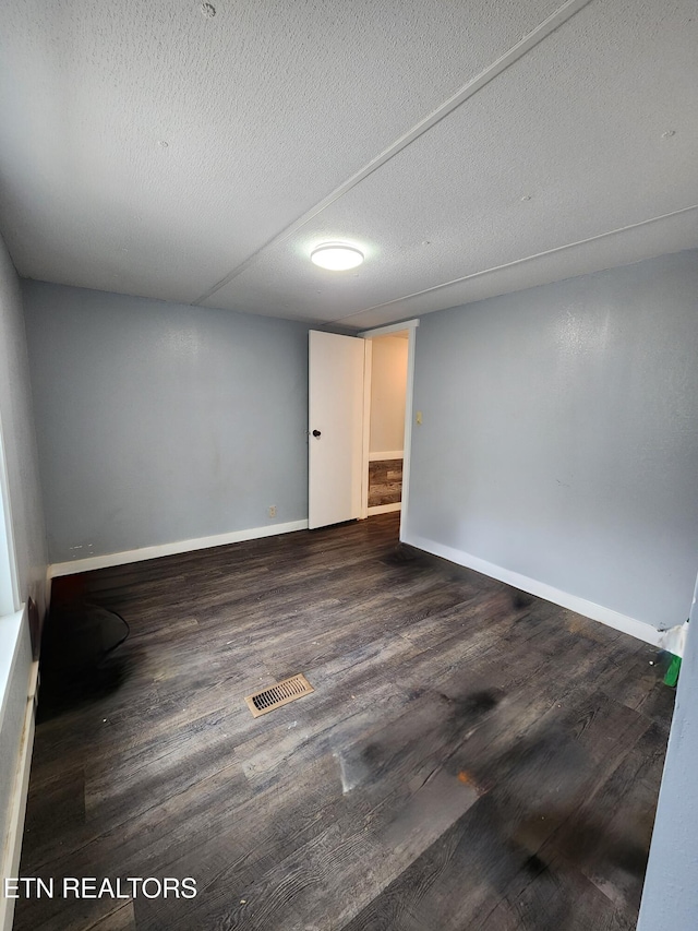 unfurnished room featuring dark wood-type flooring and a textured ceiling