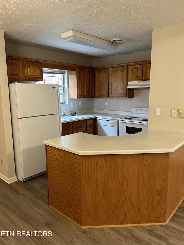 kitchen featuring dark hardwood / wood-style flooring, a textured ceiling, white appliances, and kitchen peninsula