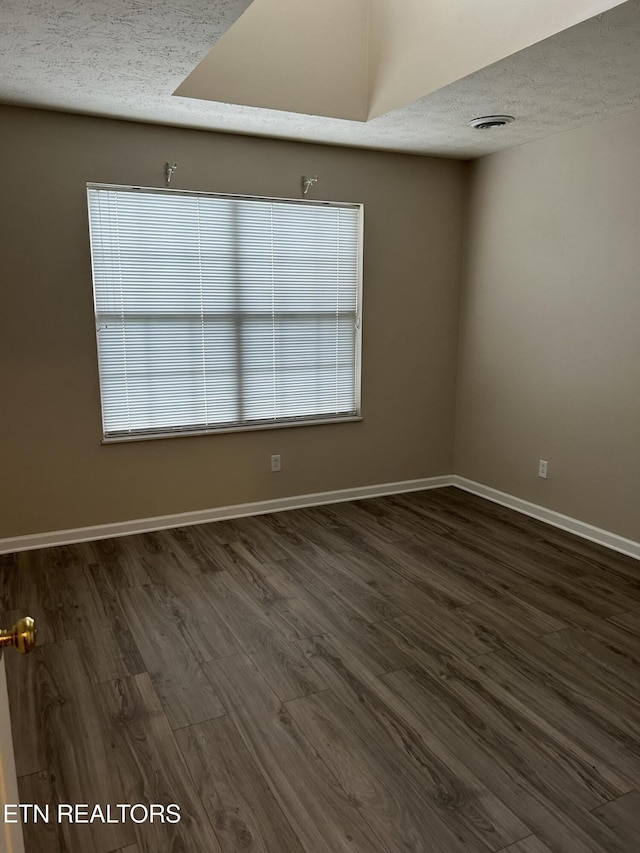 empty room with dark wood-type flooring and a textured ceiling