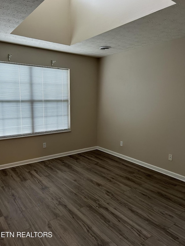 empty room with dark hardwood / wood-style floors and a textured ceiling