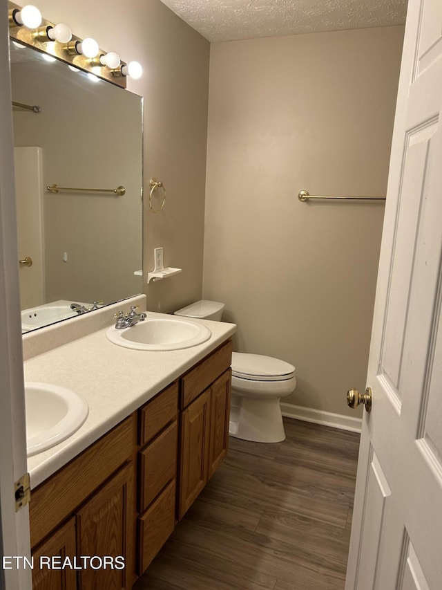 bathroom with vanity, hardwood / wood-style floors, toilet, and a textured ceiling