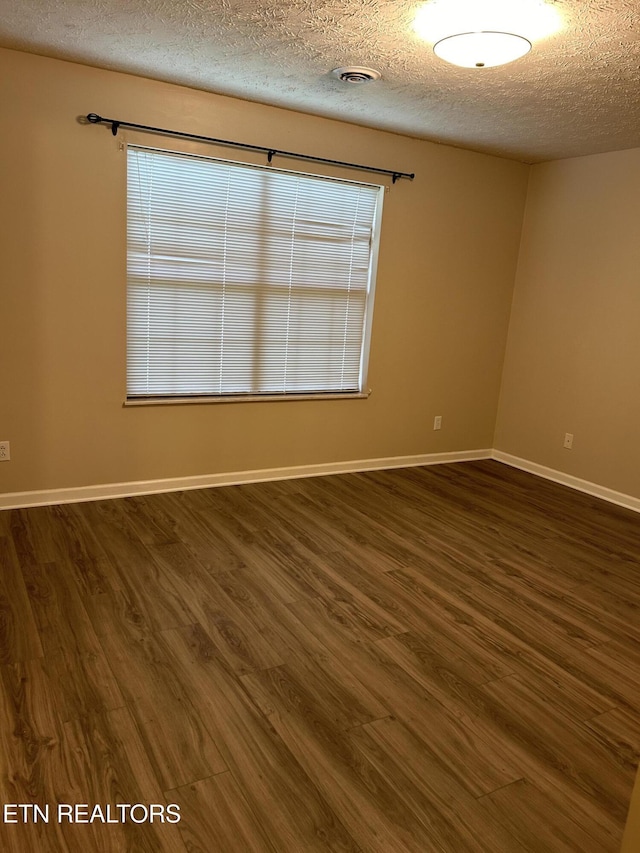 spare room with dark hardwood / wood-style floors and a textured ceiling