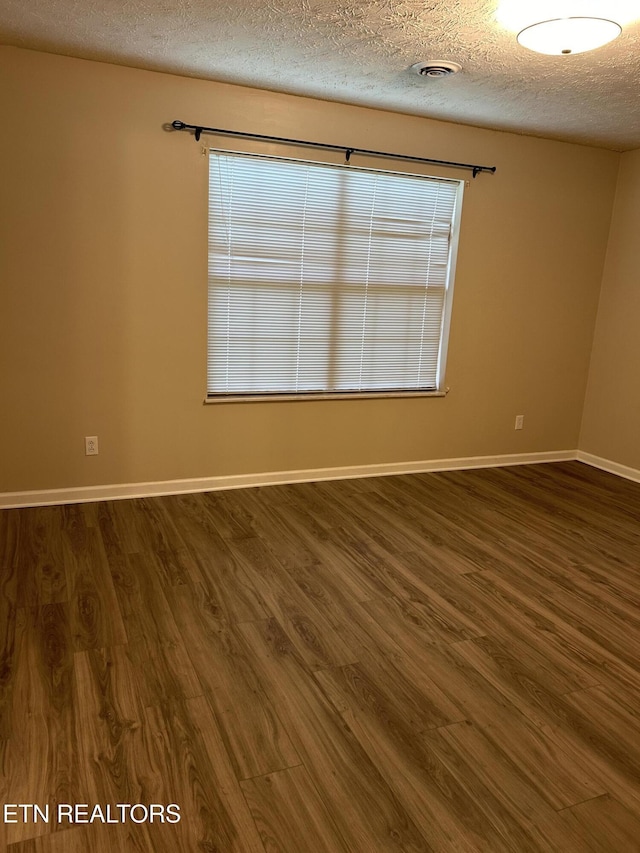 unfurnished room featuring dark hardwood / wood-style floors and a textured ceiling