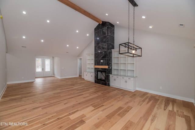 unfurnished living room featuring a high end fireplace, beam ceiling, and light wood-type flooring