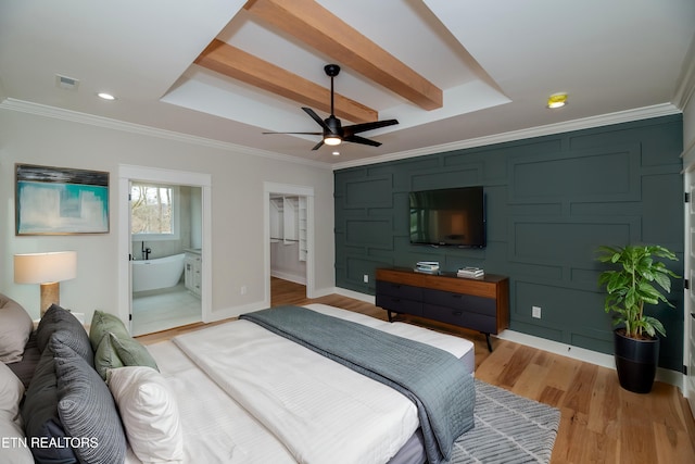 bedroom with visible vents, baseboards, a tray ceiling, light wood-style flooring, and crown molding