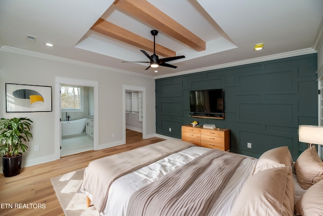 bedroom featuring light wood finished floors, visible vents, baseboards, a tray ceiling, and ornamental molding