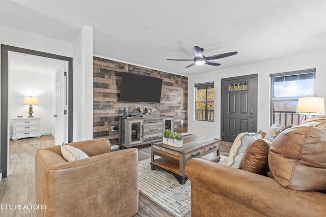 living room with hardwood / wood-style flooring, ceiling fan, and wooden walls