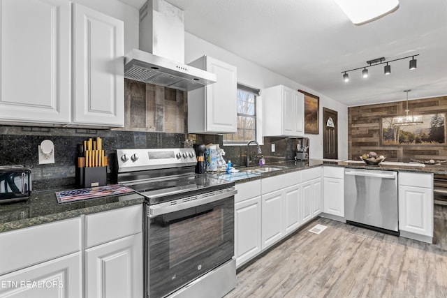 kitchen featuring white cabinetry, light hardwood / wood-style flooring, stainless steel appliances, and wall chimney range hood