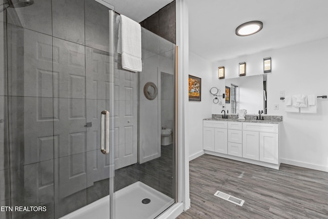 bathroom featuring walk in shower, vanity, wood-type flooring, and toilet