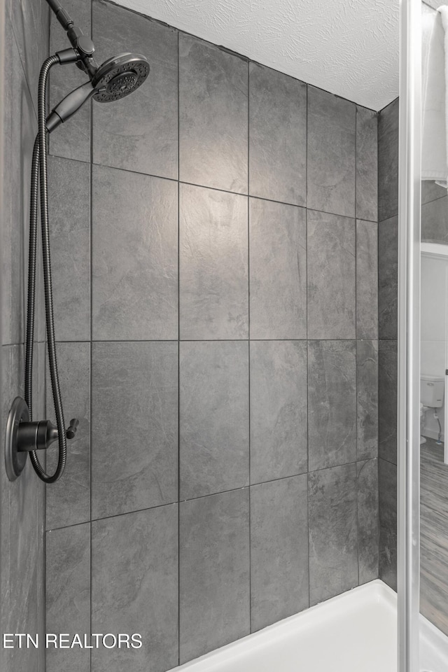 bathroom featuring a textured ceiling and tiled shower