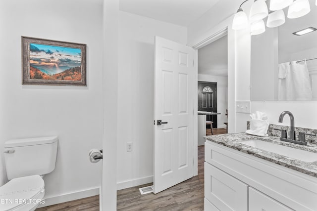 bathroom with toilet, vanity, and hardwood / wood-style flooring