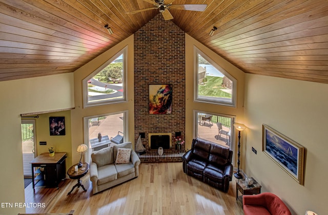 living room with light hardwood / wood-style floors, wood ceiling, high vaulted ceiling, and a brick fireplace