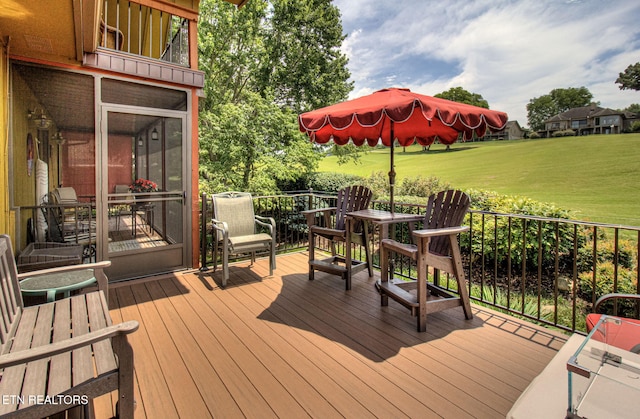 wooden terrace with a lawn and a sunroom