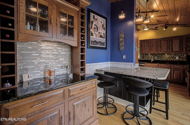 bar with decorative backsplash, dark stone counters, wood ceiling, light hardwood / wood-style floors, and lofted ceiling