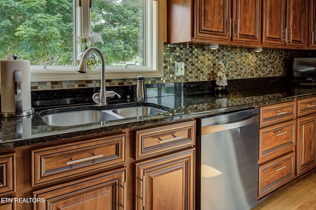 kitchen featuring dishwasher, dark stone countertops, light wood-type flooring, and sink