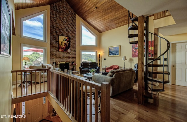 living room featuring wooden ceiling, wood-type flooring, high vaulted ceiling, and a brick fireplace