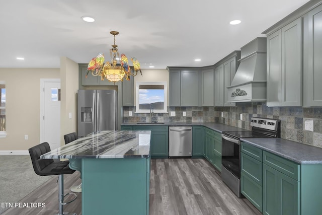 kitchen featuring sink, hanging light fixtures, a kitchen breakfast bar, appliances with stainless steel finishes, and custom exhaust hood