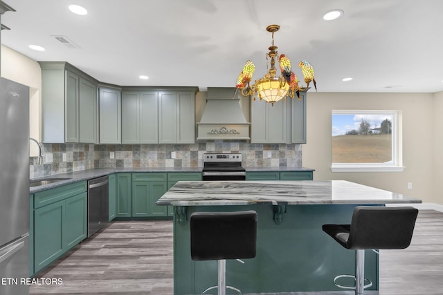 kitchen with sink, stainless steel appliances, light hardwood / wood-style flooring, decorative light fixtures, and custom range hood