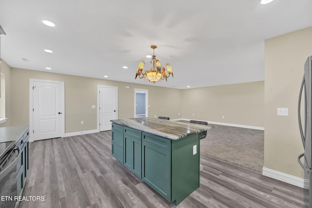 kitchen featuring a center island, hanging light fixtures, light hardwood / wood-style flooring, stainless steel refrigerator, and a chandelier