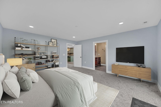 bedroom with ensuite bathroom and light colored carpet