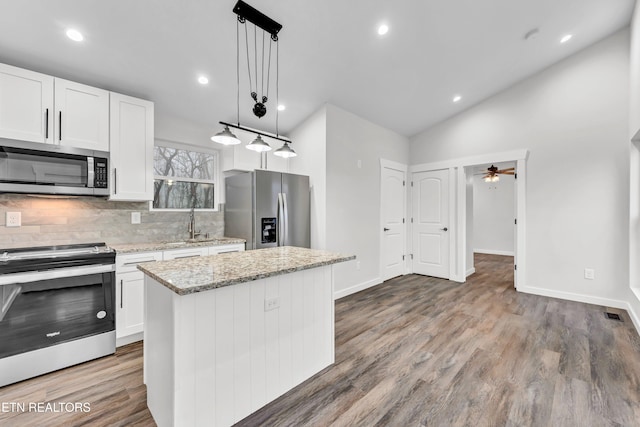 kitchen featuring pendant lighting, a center island, white cabinets, ceiling fan, and appliances with stainless steel finishes