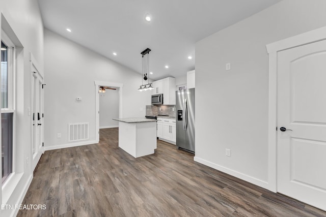 kitchen featuring white cabinetry, a center island, hanging light fixtures, stainless steel appliances, and vaulted ceiling