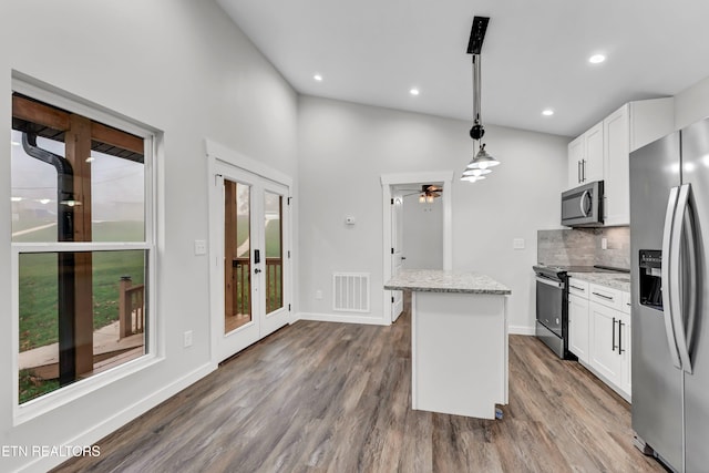 kitchen featuring white cabinetry, ceiling fan, stainless steel appliances, decorative light fixtures, and a kitchen island