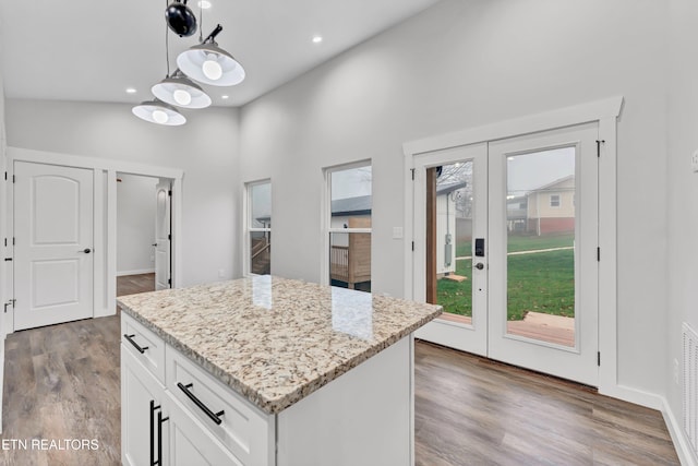 kitchen with pendant lighting, a center island, wood-type flooring, and white cabinetry