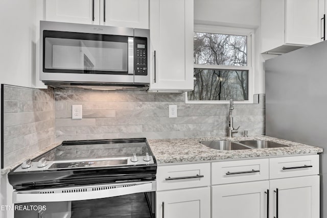 kitchen with light stone counters, sink, white cabinetry, and stainless steel appliances