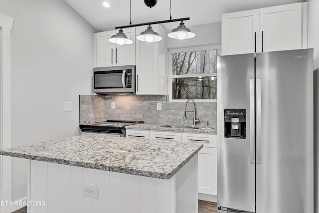 kitchen with sink, stainless steel appliances, pendant lighting, decorative backsplash, and white cabinets