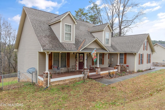 cape cod home with covered porch and a front lawn